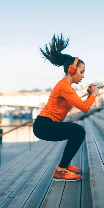 Une femme en tenue de sport s'étire la jambe.