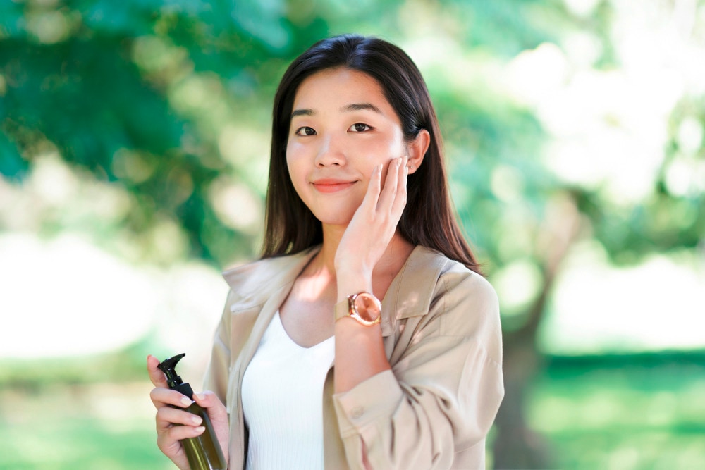 Woman reapplying her sunscreen while strolling outdoors.