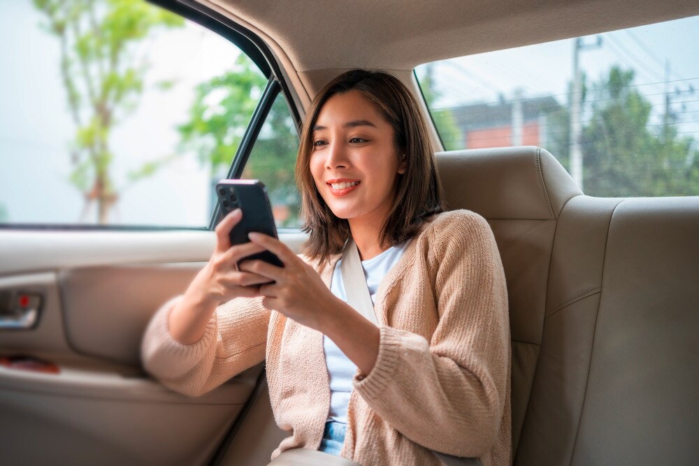 Woman playing on her phone while in a car.