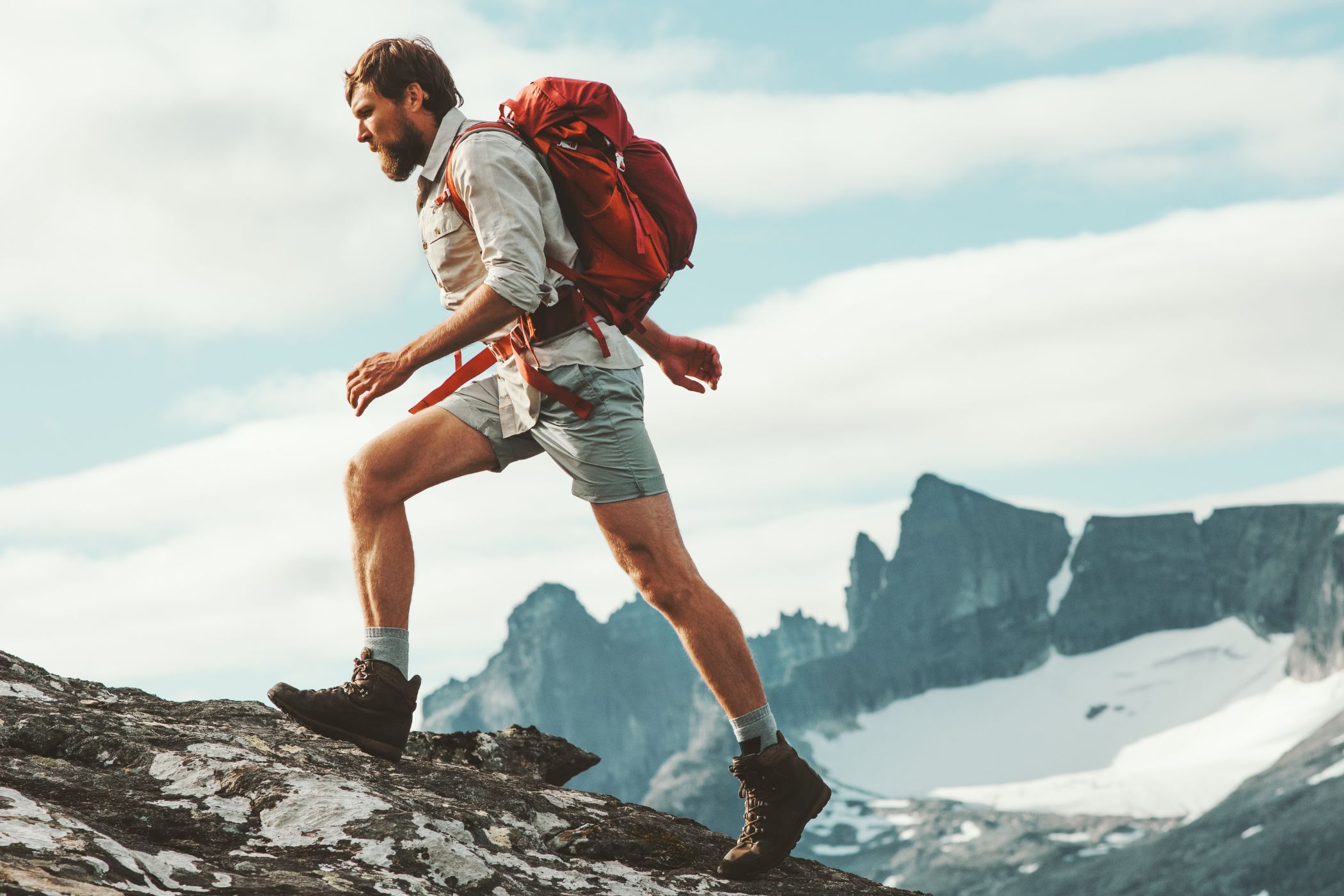 Man with beard on a hike with snowcapped mountains background