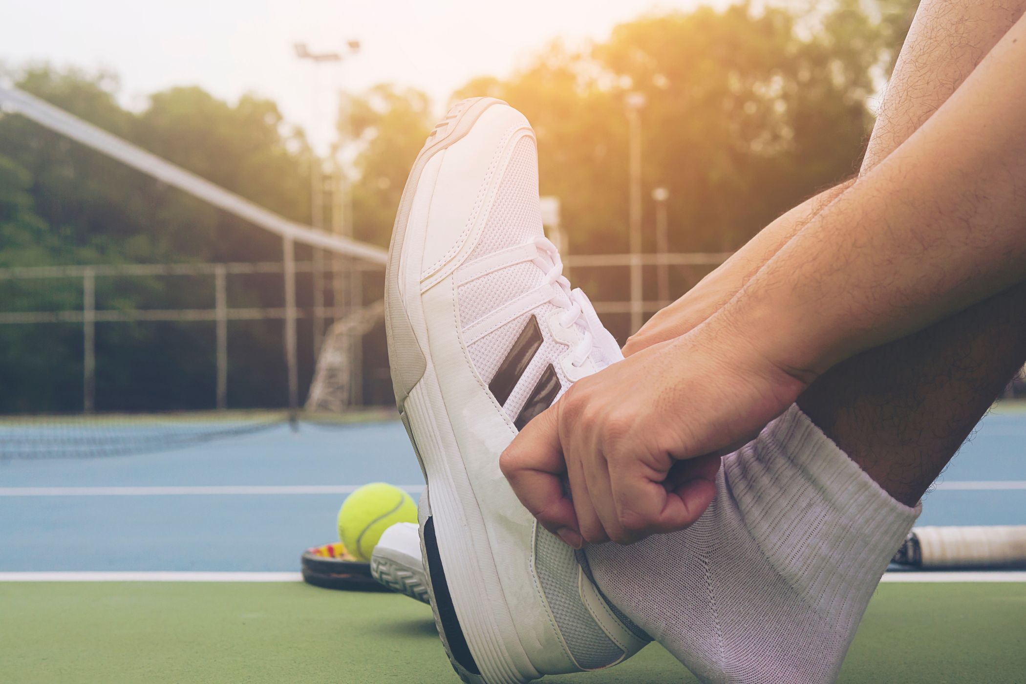 Man putting on socks with sneakers in the background.