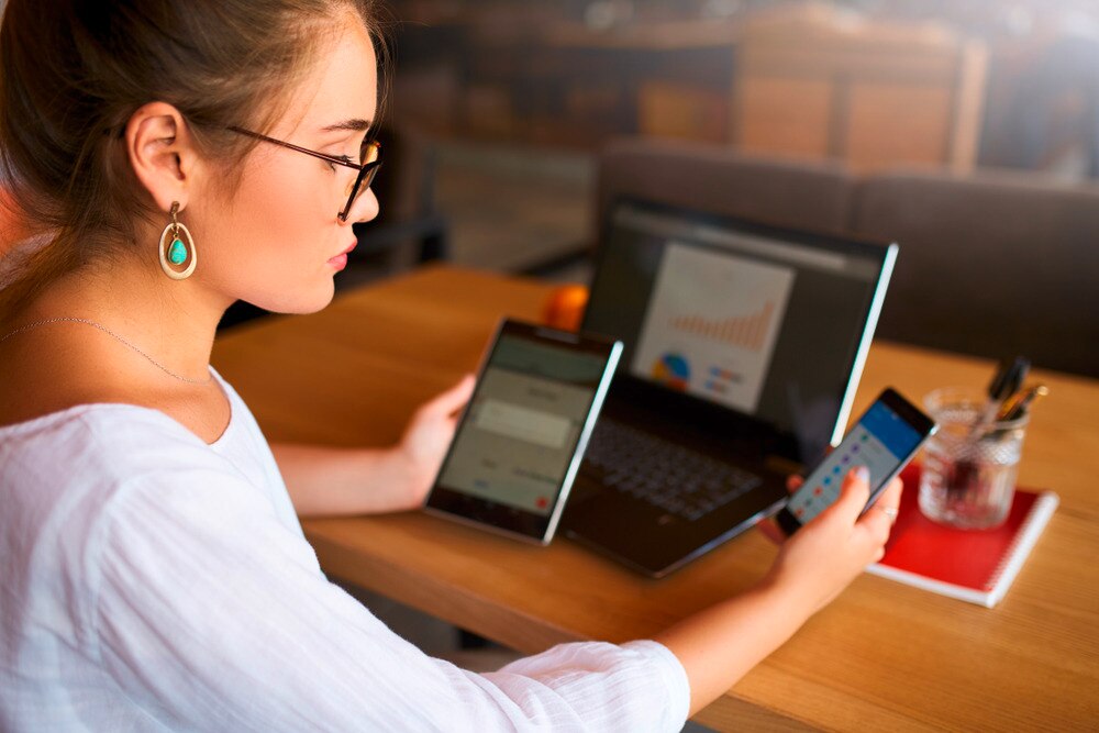 Asian woman looking at three screens.