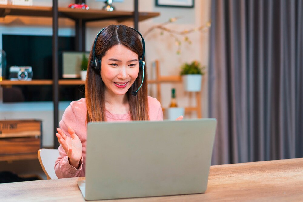 Asian woman using laptop for work meeting.