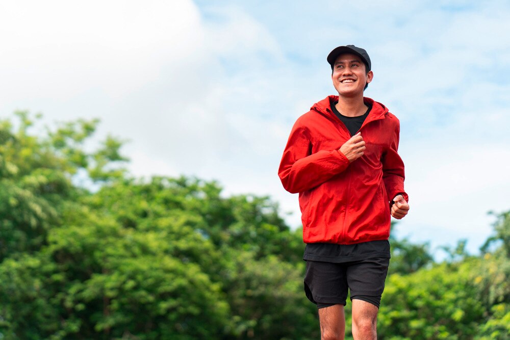 Asian man running in a park.