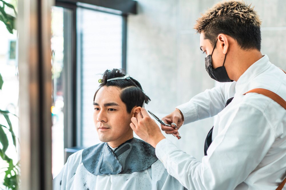 A portrait of man getting his hair cut at a barbershop.