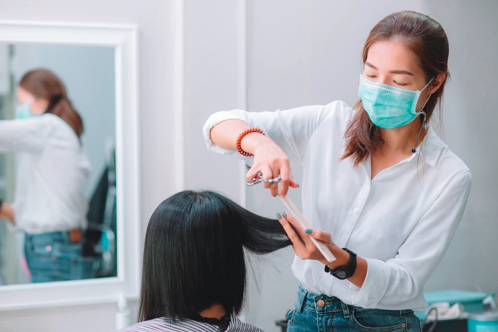 A hairdresser trimming a woman’s short hair at the salon.
