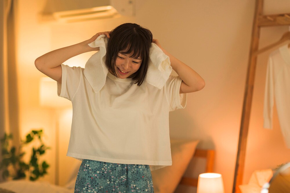 Woman rubbing a towel on her head while air-drying her hair.