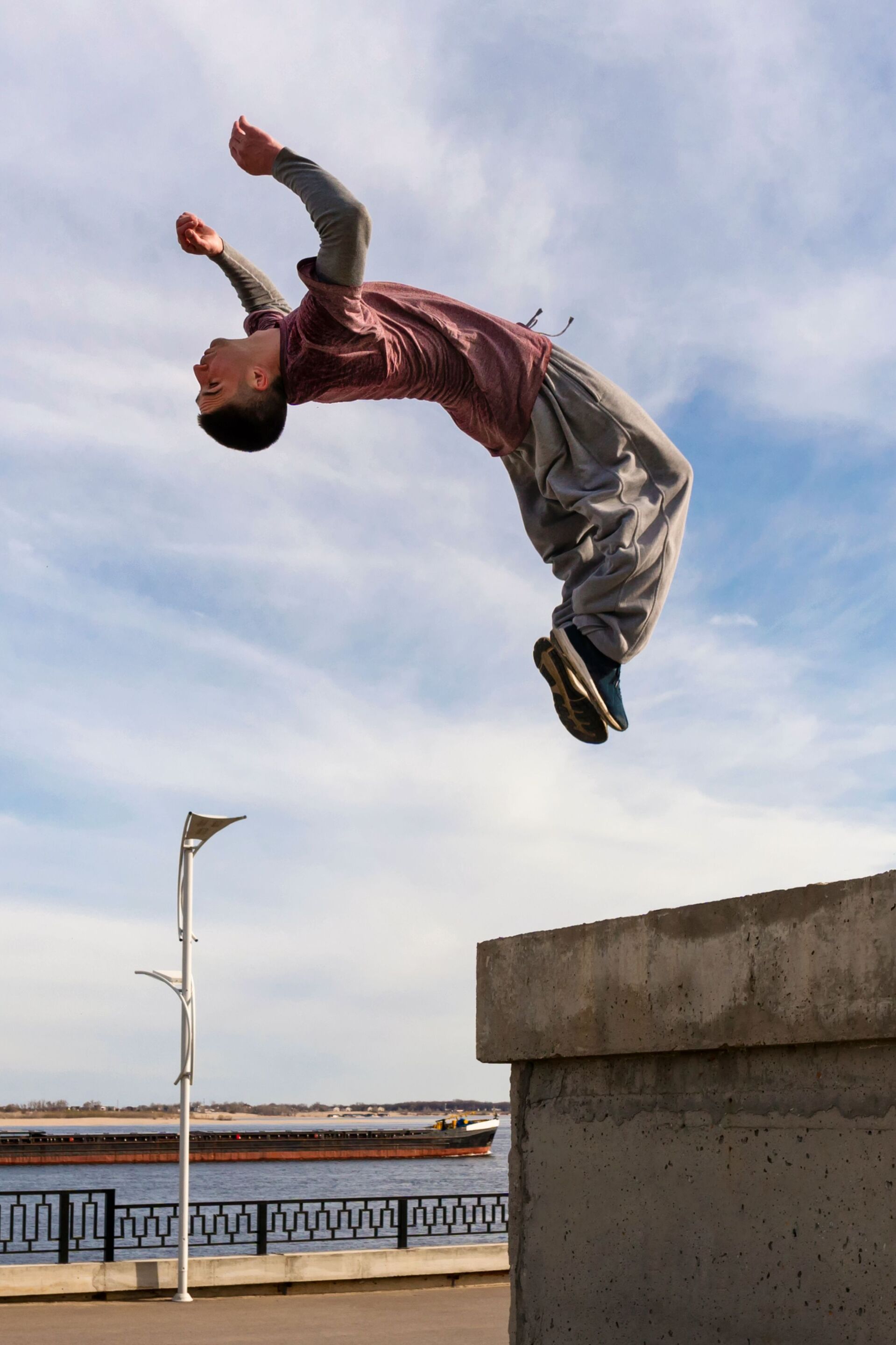 Image depicts young boy jumping somersault on street.
