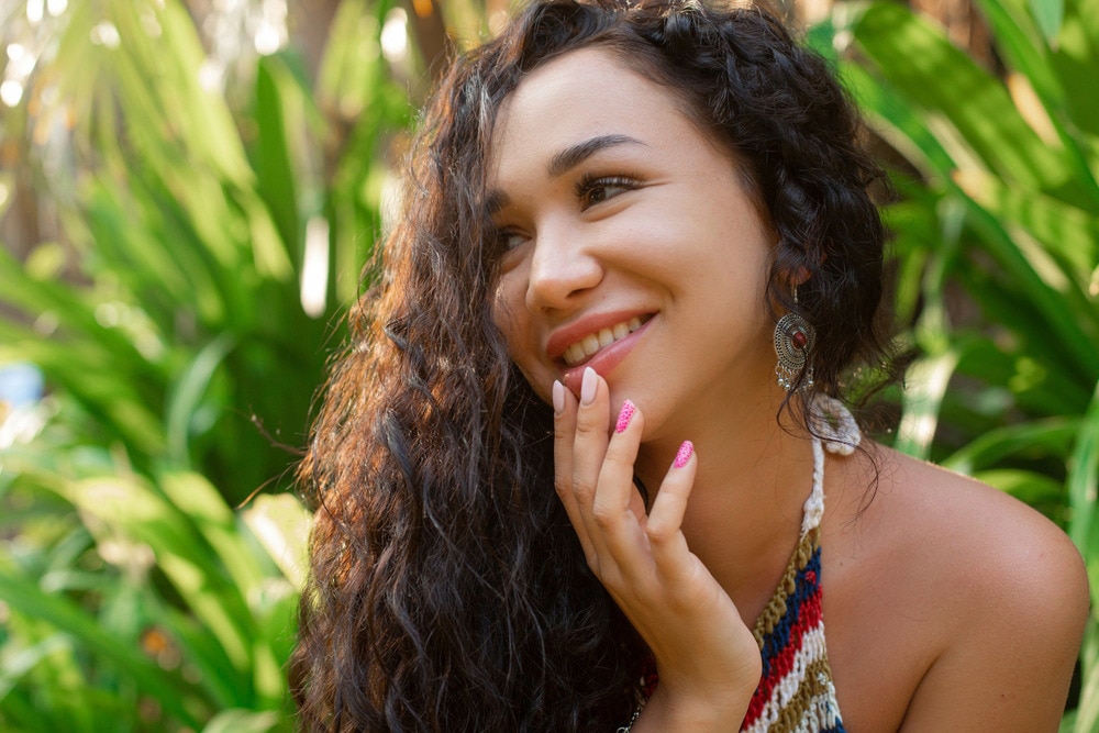A portrait of smiling woman with thick, curly hair.