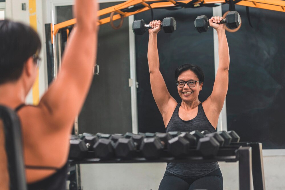 Woman with short hair lifting weights at the gym.