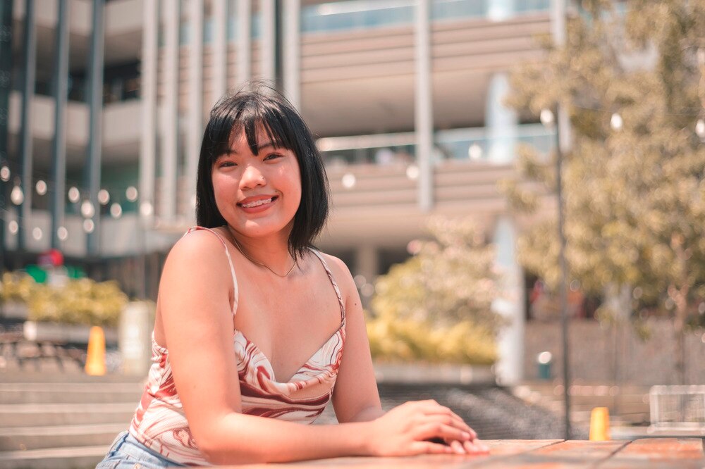 Woman with short hair and strappy top smiling to the camera.