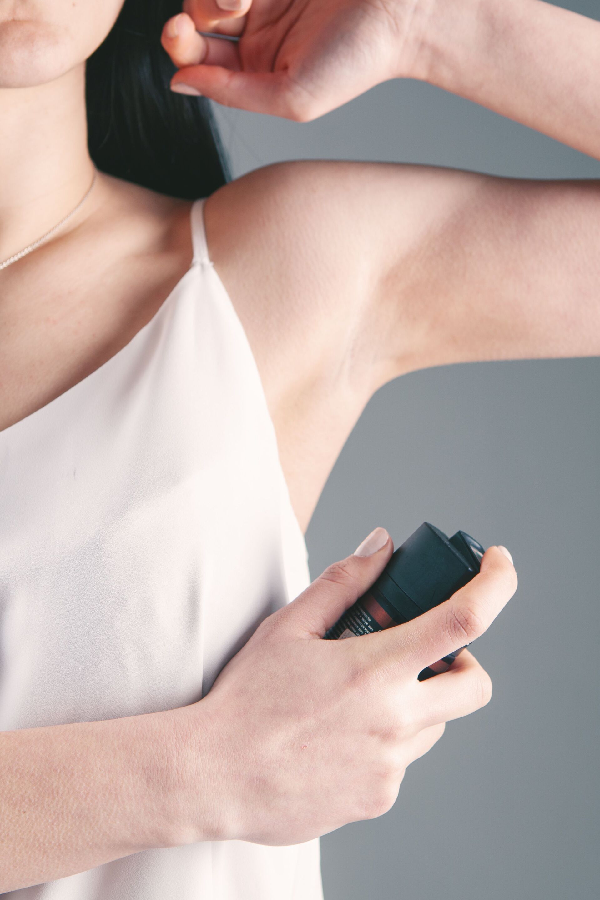 Young girl spraying aerosol deodorant on her armpit