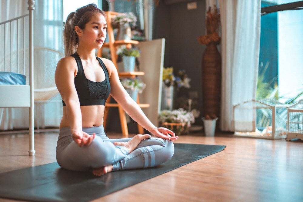 Woman sitting cross-legged on a yoga mat.