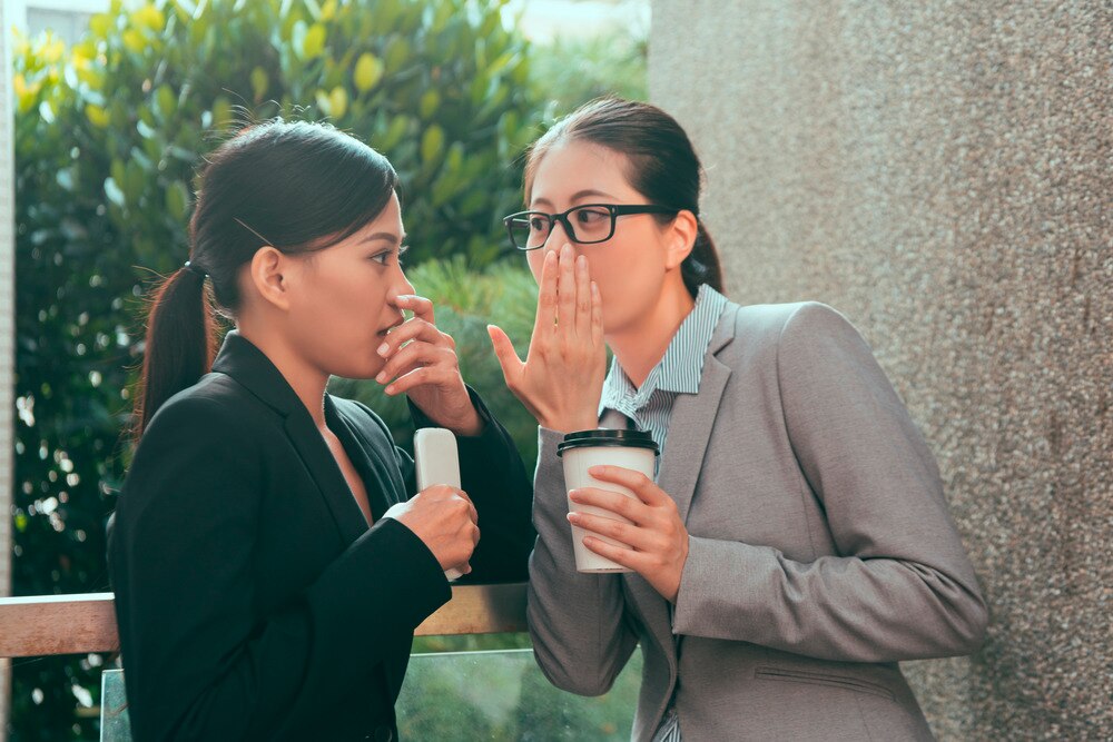 Two female office workers gossiping.