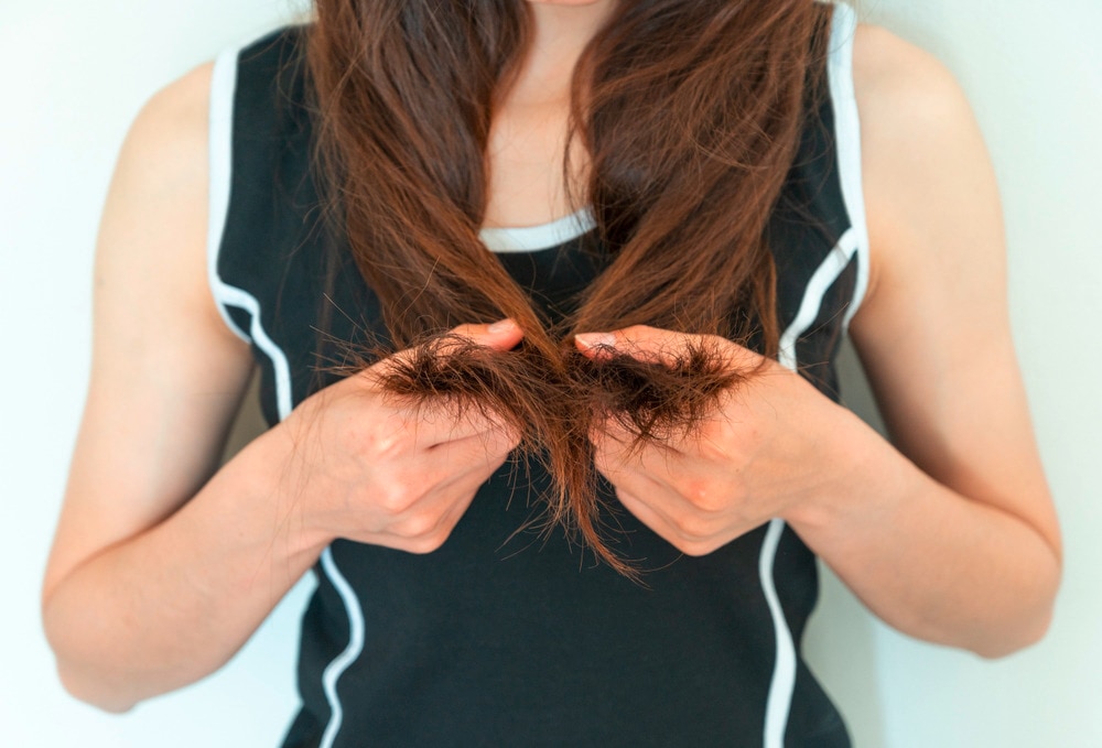 Woman holding her long, damaged hair.