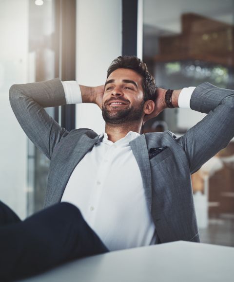 Confident business man in the boardroom raising his arms