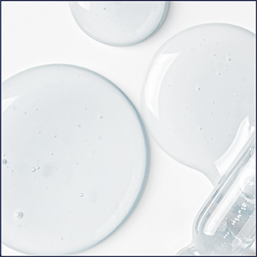 A person is shown standing on a beach and smiling. They are turned to the side and facing the camera.