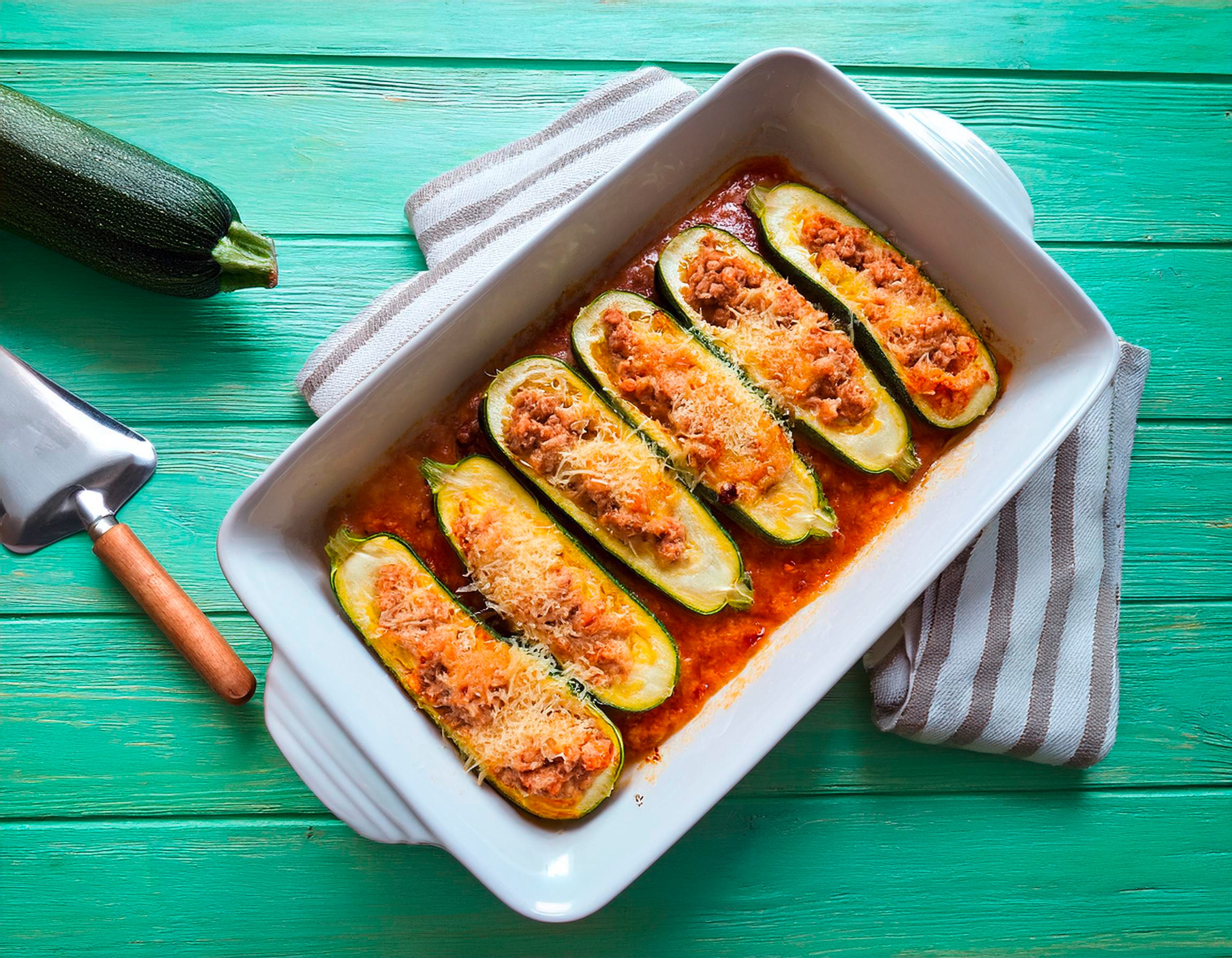 Eine Auflaufform mit halbierten Zucchini drin, die mit Hack gefüllt und Käse überbacken sind