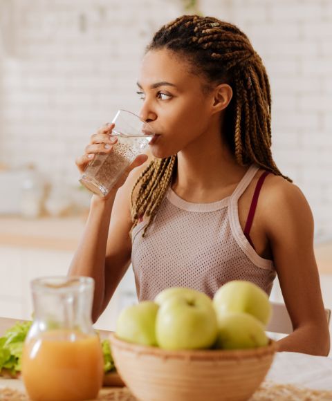 Mujer joven bebiendo agua y comiendo fruta fresca