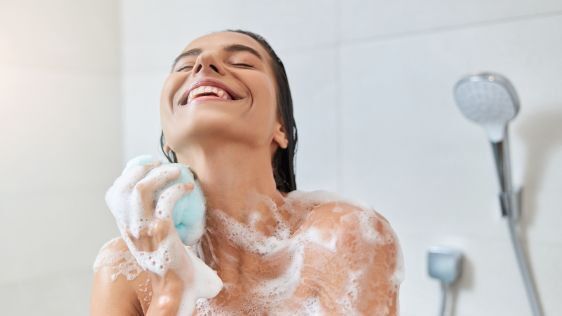 Happy woman taking a shower and using shower gel