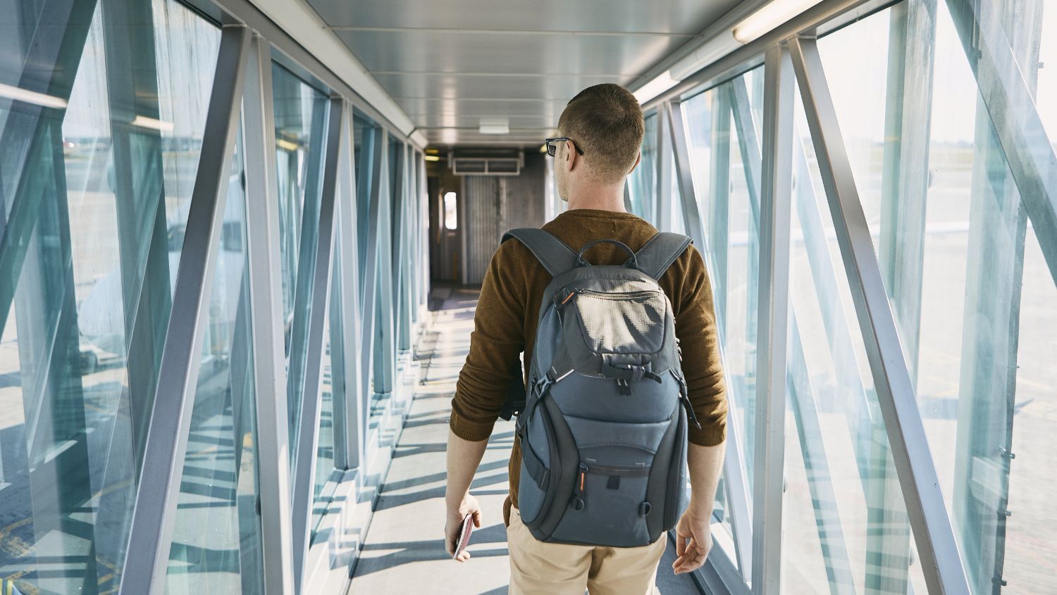 Young man boarding a plane wearing a backpack
