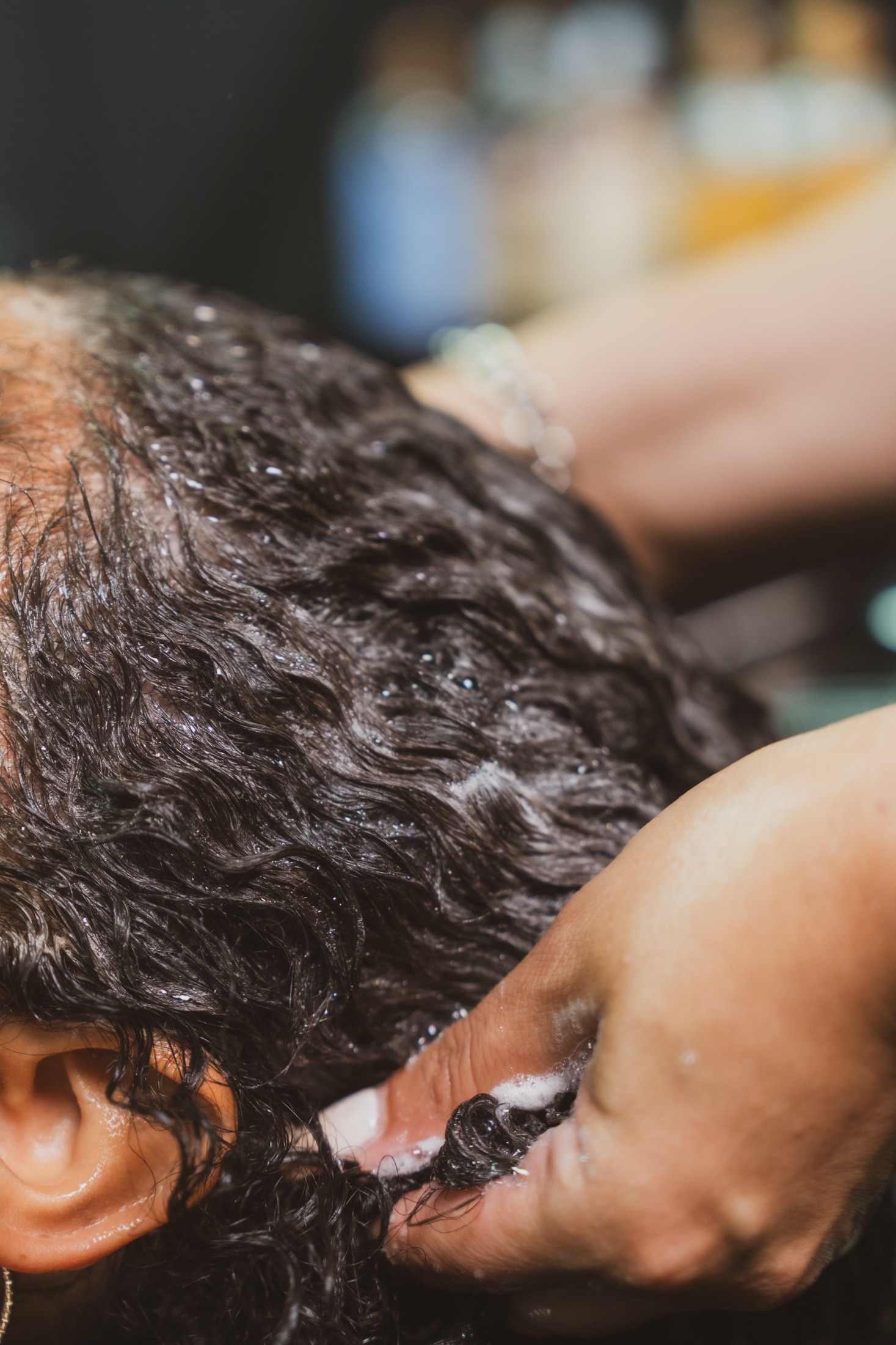 A curly-haired client getting her hair shampooed in a professional salon setting.