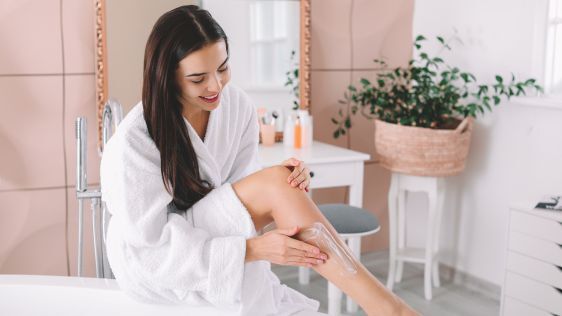 Woman applying body cream after a shower