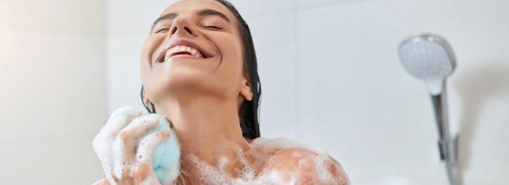 Happy woman taking a shower and using shower gel