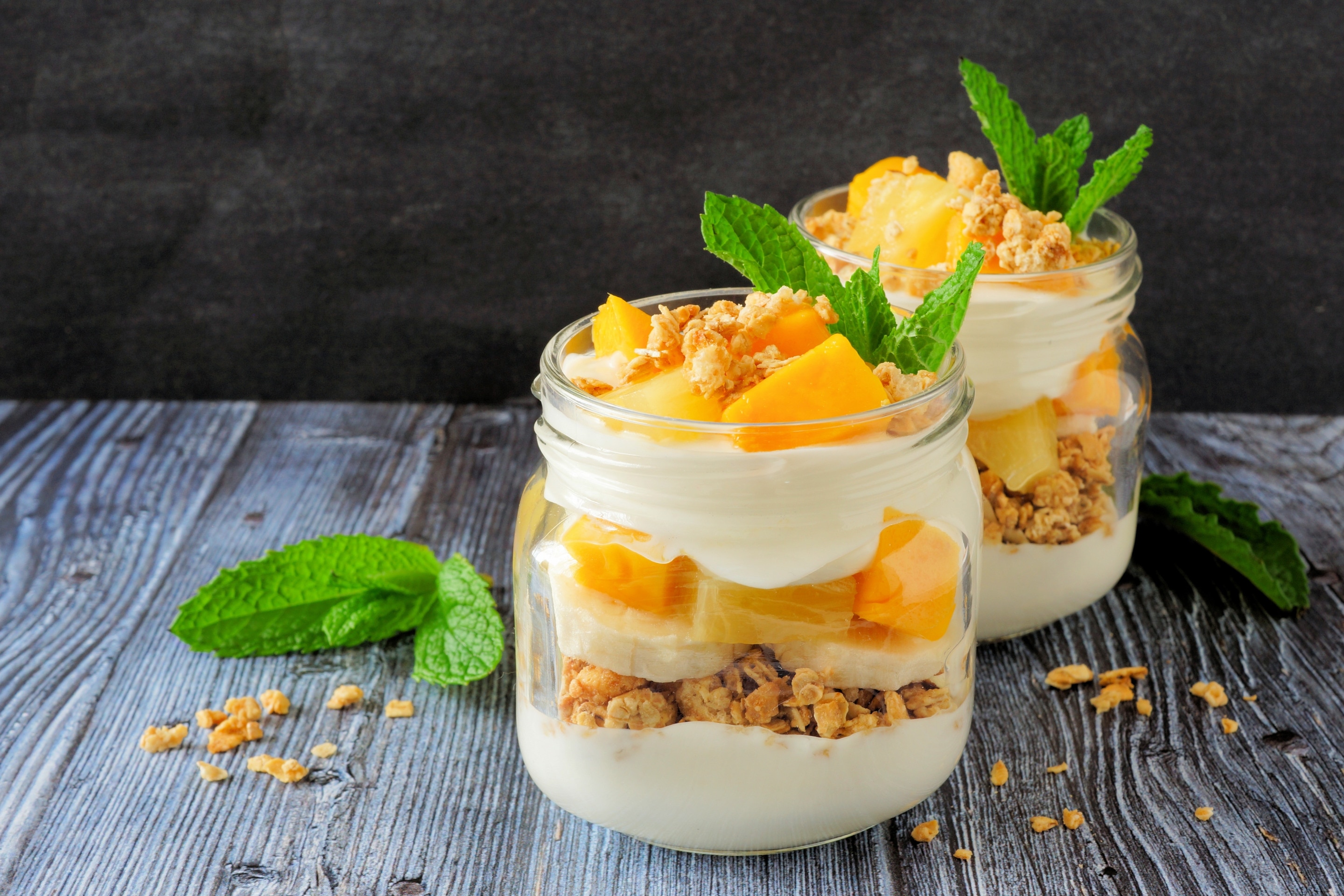 Two glasses of mango parfaits on a wooden table.