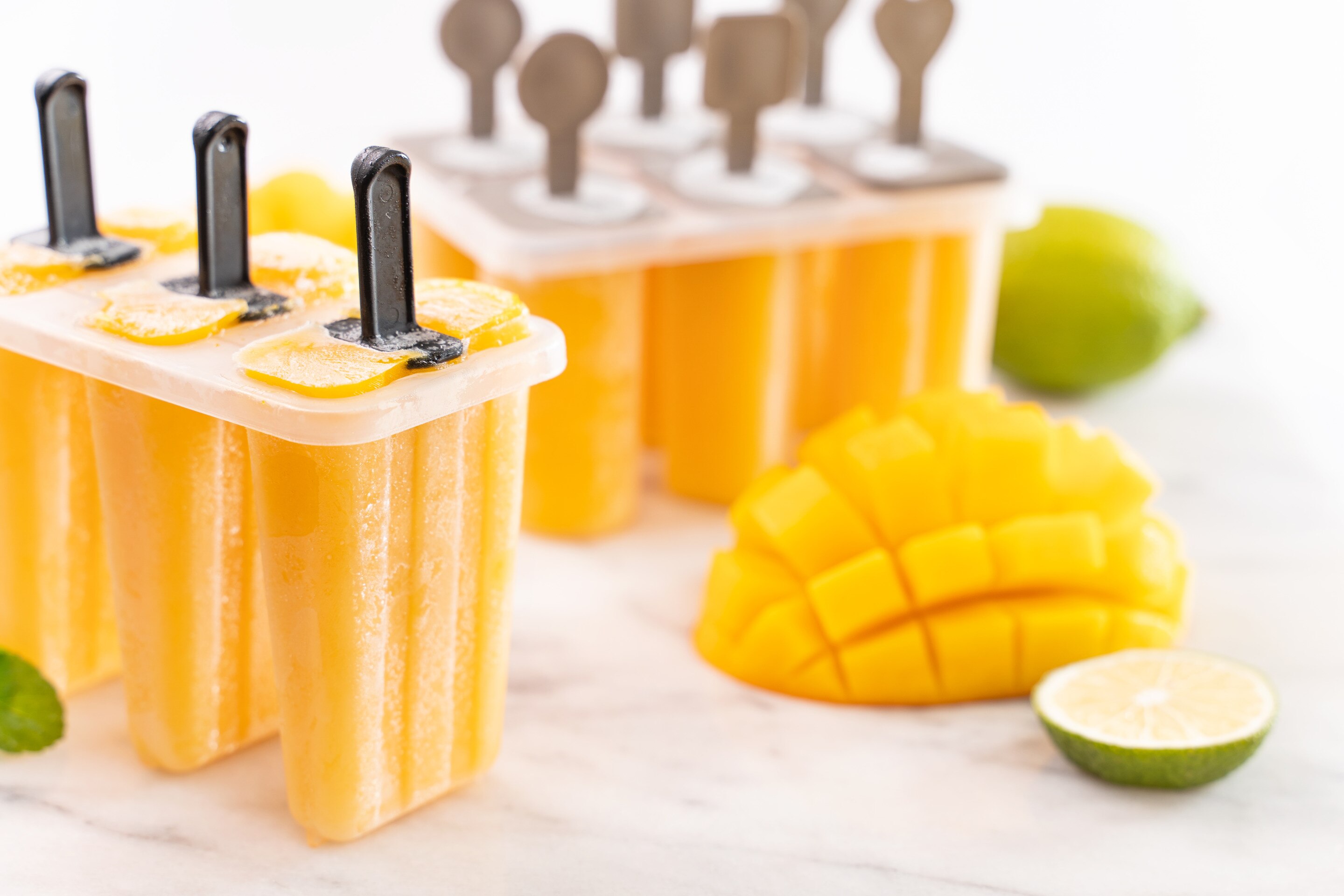 Homemade mango cream popsicles on a white countertop.