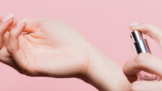 Woman spraying perfume on pulse points