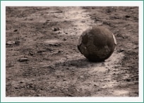 Foto de uma bola desgastada em um chão de areia