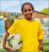 Menina sorrindo com uma blusa amarela e uma bola de futebol