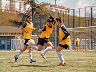 Três mulheres jogando futebol