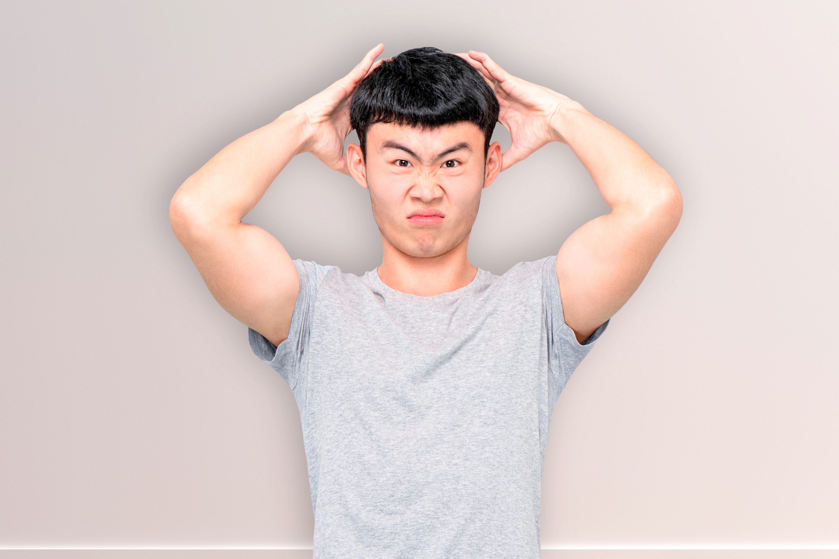 pria asia yang sedang mengangkat tangannya untuk menunjukkan ketiak bau bawang