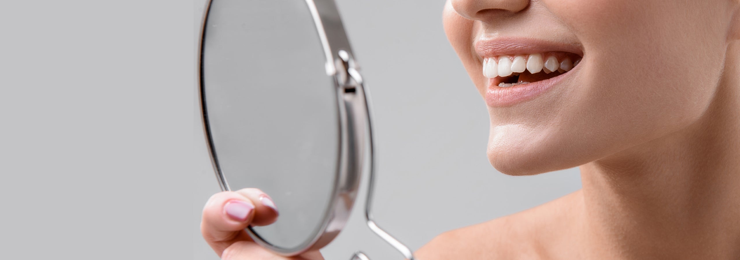 close-up of a woman inspecting her white teeth in the mirro