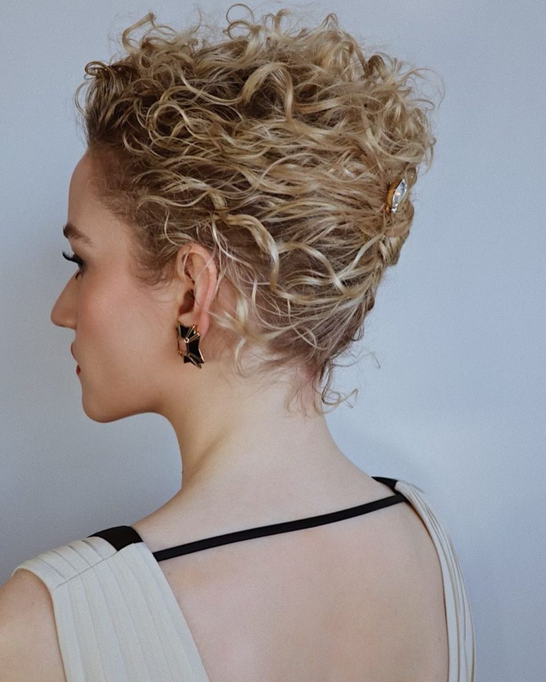 Julia Garner in a white dress with blonde curly French twist.