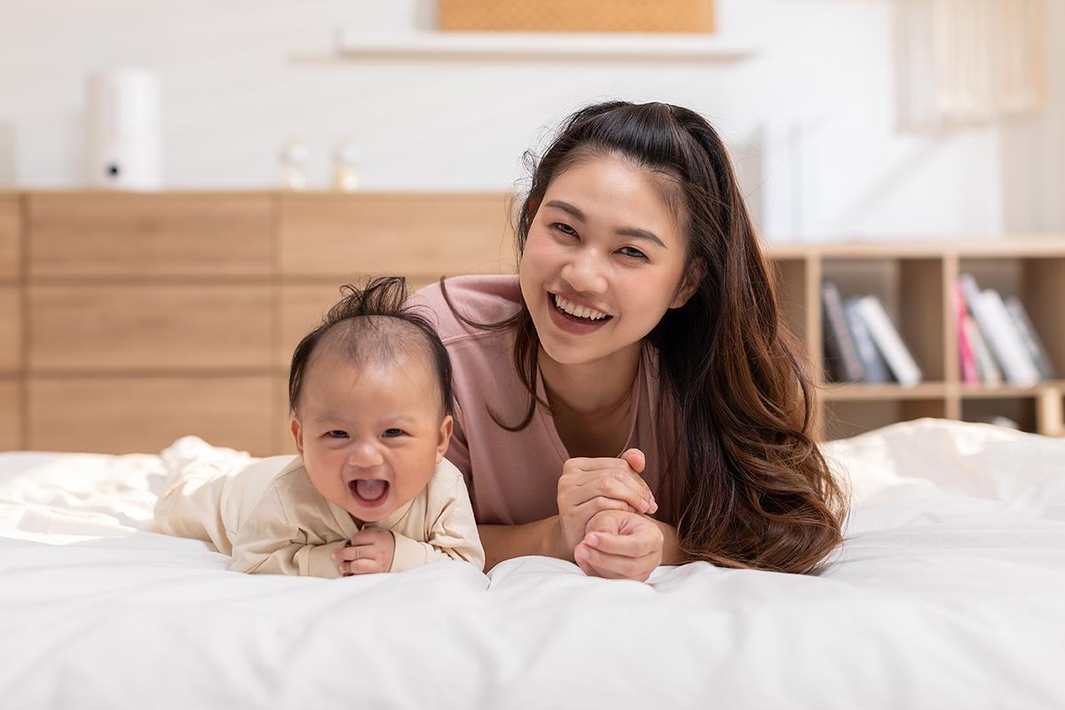 Asian mom with baby on bed 