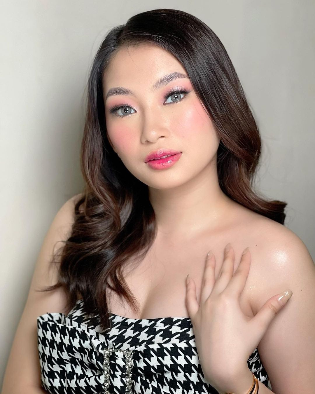 A portrait of Angela Kano with printed top and pink makeup.