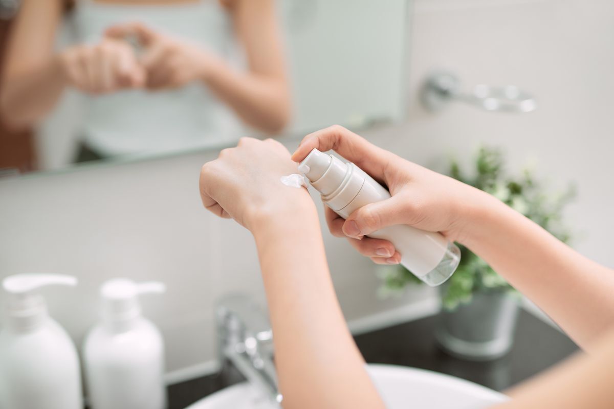 Woman pumping out a moisturizing cream on the back of her hand. 