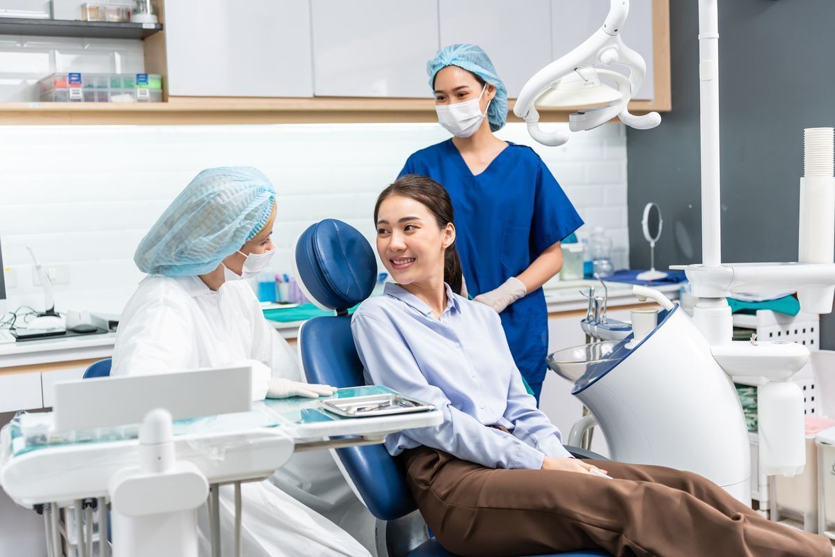 An Asian woman talking to a dentist in a dentist’s office.