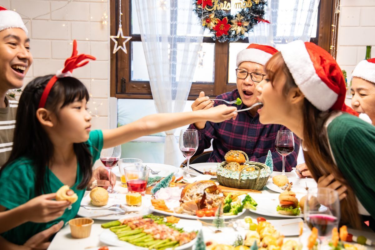 Little Asian girl feeding mom during Christmas feast