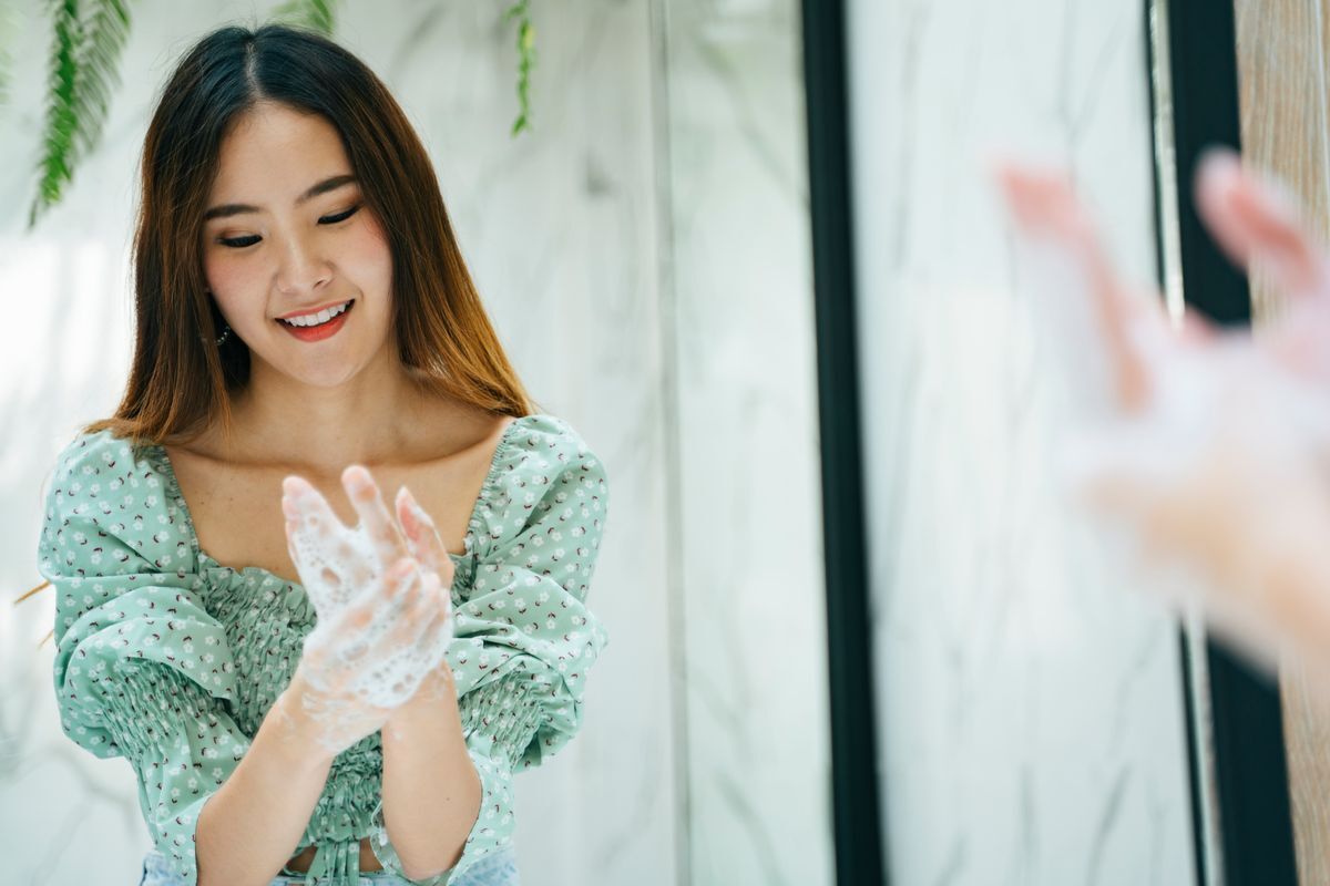 Asian woman washing her hands in front of the mirror