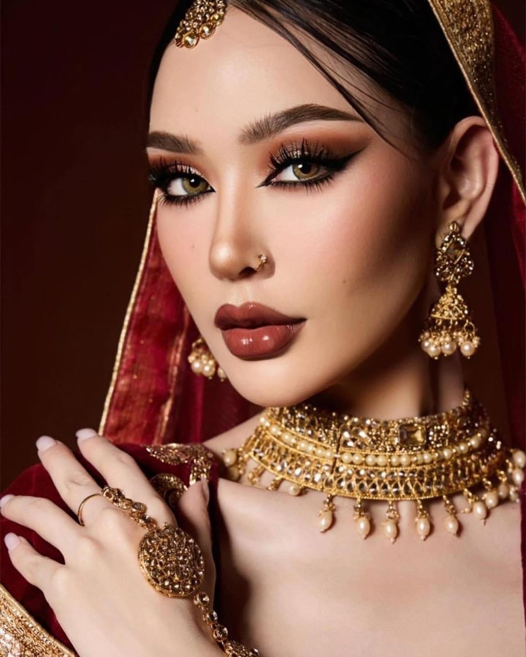 A photo of woman with smokey eyes, cat eyeliner, drawn-in eyebrows, and glossy lips.