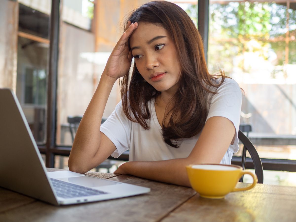Girl sitting in front of her laptop, trying to think
