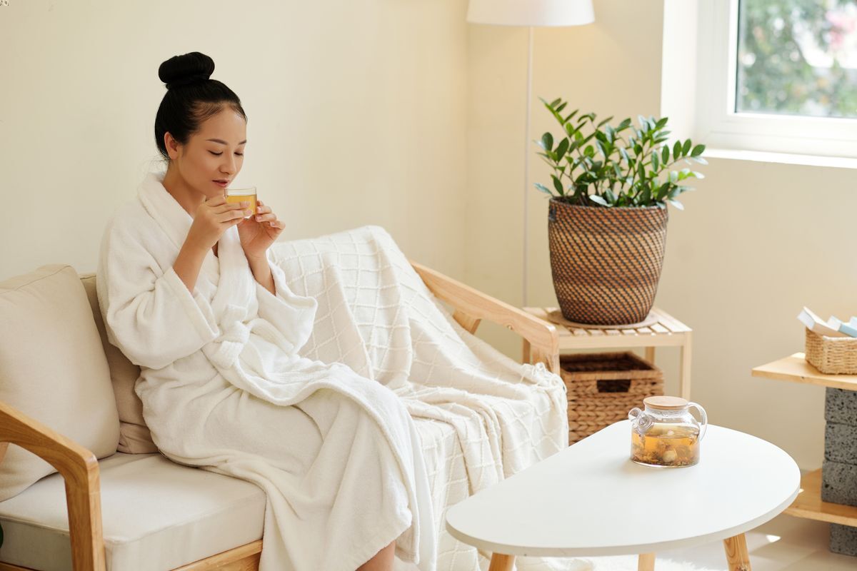 Asian woman in a robe sipping tea