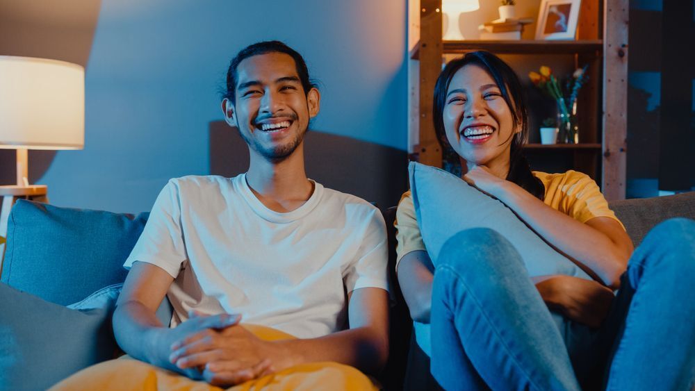 A couple watching movie at home while sitting on a sofa.