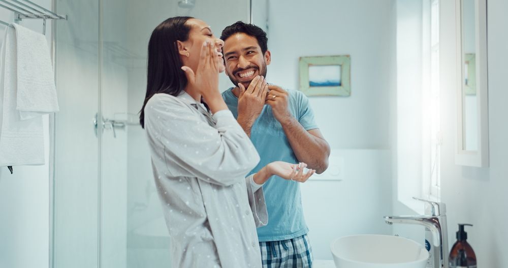 Man and woman putting on skincare together in the bathroom.