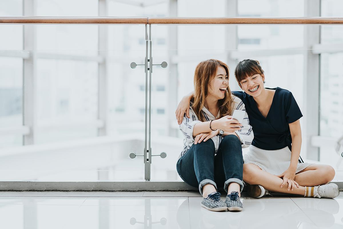 Asian friends sitting on the floor and laughing