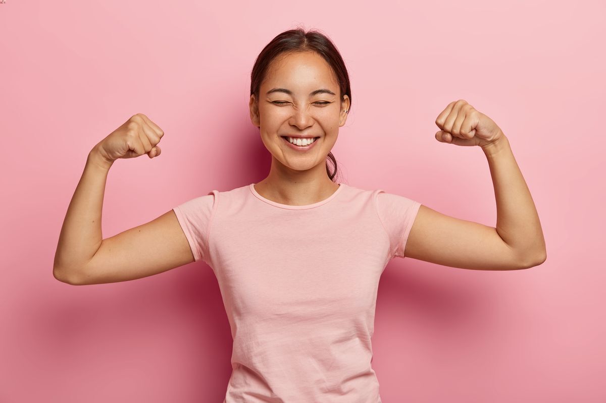 Asian woman holding up her arms in a show of strength